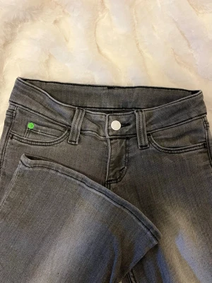 Weekday Jeans - Snygga grå jeans med raka ben och klassisk femficksdesign. Jeansen har en unik detalj med ett grönt knapphål på myntfickan och silverfärgad knapp framtill. Perfekta för en avslappnad och trendig look. Dem är Lågmidjade!