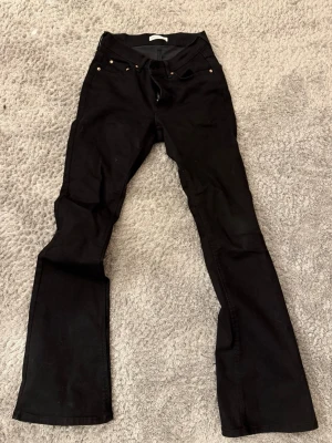 Svarta bootcut jeans från Perfect Jeans - Svarta low-waist jeans med bootcut-modell från Perfect Jeans. Klassisk femficksdesign, hällor för bälte och snygga kopparfärgade nitar. Jeansen har en stilren look och är tillverkade i ett stretchigt material för skön passform. Jag har endast använt dessa två gånger så de är nästan som nya!! 