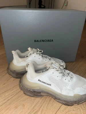 Balenciaga Triple S vita chunky sneakers - Säljer ett par vita Balenciaga Triple S sneakers. Köptes på balenciagas egen hemsida för 895€ år 2021 och är knappt använda sedan dess. Flärpen på baksidan av ena skon är lös - se bild.