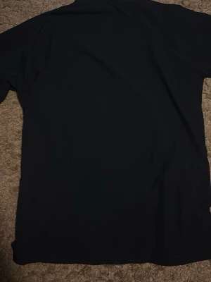 Nike Dri-FIT svart träningsjacka - Svart träningsjacka från Nike med vit dragkedja och Dri-FIT-teknologi. Jackan har hög krage, vita detaljer längs axlarna och två fickor framtill. Perfekt för sport och träning, med en clean och sportig look.