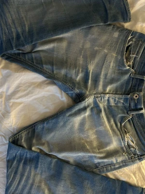 Dondup jeans  - Säljer ett par blå jeans med slitningar och hål vid fickan. Jeansen har en klassisk femficksmodell, normal midja och dragkedja. Materialet är denim i bomull och de har en tvättad, vintage look som ger en avslappnad vibe. Storlek 31/32