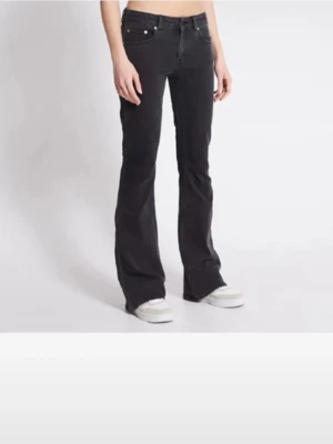 Svarta bootcut jeans med låg midja - Säljer ett par svarta bootcut jeans med låg midja och klassisk femficksdesign. Jeansen har utsvängda ben och stängs med dragkedja och knapp. Perfekta för en trendig och avslappnad look.