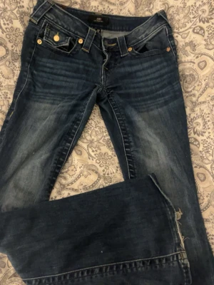True Religion bootcut jeans blå - Snygga blå bootcut jeans från True Religion med vita detaljer på fickorna. Bra kvalitet och de är köpta för 1400