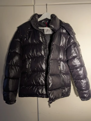 Moncler Maya Giubbotto – Ny, endast provad (M) - Säljer en Moncler Maya Giubbotto i storlek M. Jackan är helt ny, endast provad inomhus. Den var en present men är tyvärr inte min stil, därför säljs den vidare. Klassisk Maya-modell i blank laqué-nylon med fast huva och dunfyllning. NFC-chip och originaletiketter finns kvar, självklart äkta. Skickas väl emballerad eller kan hämtas enligt överenskommelse. Hör av dig vid frågor eller om du vill ha fler bilder.