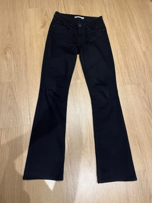 Svarta bootcut jeans från Levis - Snygga svarta jeans i bootcut från Levis. Jeansen är i stretch och midrise. OBS! Modellens namn har bytt namn till ”725”, dessa heter ”715” men det är samma modell. (Storlek 26-32)