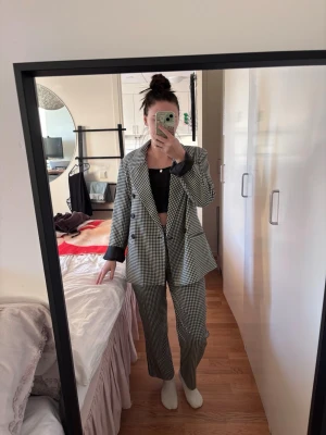 Rutig svartvit kostym  - Snygg tvådelad kostym med rutig kavaj och matchande byxor i svart och vitt. Kavajen har dubbelknäppning och klassisk krage. Perfekt för dig som vill sticka ut med stilren look. Materialet känns mjukt och följsamt. Både i storlek 32. Jag ät 160 cm. 