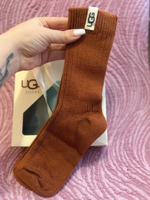 Bruna ribbade strumpor från UGG - Snygga bruna strumpor från UGG i ribbad design. Strumporna är stickade och har en klassisk form med UGG-logga på kanten. Perfekta för dig som vill ha både stil och komfort.