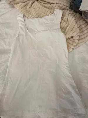 Vit linnetopp från VILA XS - Säljer en stilren vit linnetopp från VILA i storlek XS. Toppen har en enkel och klassisk design med breda axelband och rundad halsringning. Materialet är mjukt och har en lätt glansig finish som känns fräsch och somrig.