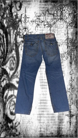True Religion jeans  - Säljer jättesnygga baggy blå jeans från True Religion med klassiska kontrastsömmar och snygga fickdetaljer. De har små defekter på framsidan som visas på bild 5 och 6. Men förutom det är dem hela och rena. 