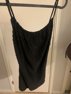 Svart topp ginatricot - Säljer en svart topp från ginatricot i storlek XS. Toppen är ribbad och har en rem vid halsringningen som är veckad och går att dra ihop om man vill. Banden går korsade på ryggen. Materialet är luftigt och skönt. En jätte snygg topp som bara kommit till användning 1 gång, är i mycket bra skick💗