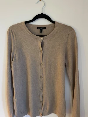 Beige kofta från Mango - Snygg beige kofta från Mango Basics med rund hals och knappar hela vägen framtill. Långärmad och tillverkad i mjuk bomullsmix