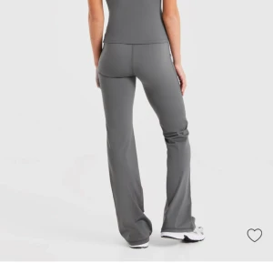  AYBL tights HELTNYA - Snygga grå bootcut träningsbyxor från AYBL med hög midja och slät yta. Byxorna har en figurnära passform upptill och blir vidare nedtill, vilket ger en modern siluett. Tillverkade i mjukt och stretchigt syntetmaterial som är perfekt för träning.