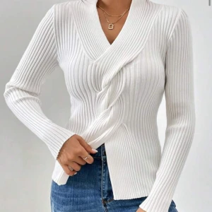 Vit omlott ribbad tröja - Snygg vit omlott-tröja med ribbad struktur och v-ringad hals. Tröjan har långa ärmar och sitter snyggt med en normal passform. Perfekt att matcha med jeans eller kjol för en fräsch look.