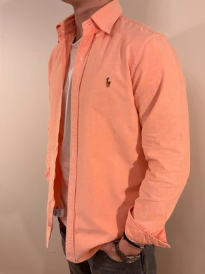 Rosa Ralph Lauren skjorta - En stilren skjorta från Ralph Lauren. Second hand men i väldigt fint skick ✨ Tvättad och struken – redo att användas direkt.  Riktigt snygg för många olika tillfällen såsom fest eller i vardag. Vinter eller sommar men bäst på vår/sommar. Inga defekter och regular fit.  Storlek 👔: S Nypris 💰: ca 1 300 kr 