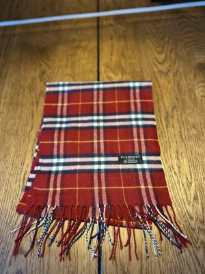 Röd Burberry Halsduk - Säljer en rutig halsduk från Burberry. Skriv om du har frågor,