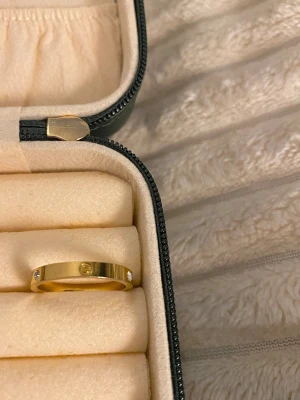 Guldfärgad ring med stenar - Guldfärgad Stainless steel ring, slitstark! Allergi vänlig, Vatten tålig och färgen försvinner! Finns även i samma model i storlek 9 i både silver och guld . Har en rund form och små infällda stenar runt om. Ringen har en modern look och passar till många olika stilar. 