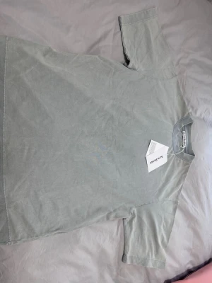 Ljusgrå t-shirt från Acne Studios - Säljer en stilren ljusgrå t-shirt från Acne Studios i storlek S. T-shirten är tillverkad i 100% bomull och har en klassisk rund hals samt korta ärmar. Perfekt för dig som gillar minimalistisk design och vill ha ett plagg med premiumkänsla.