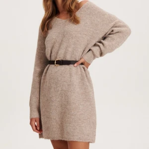 Beige stickad klänning Reserved - Mysig beige stickad klänning från Reserved i storlek M. Klänningen har v-ringad hals, lång ärm och är ribbstickad i ett mjukt ullmaterial. Perfekt för dig som gillar en loose och avslappnad passform med enkel design.