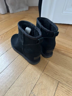 Svarta UGG boots i mocka, storlek 37 - Säljer ett par svarta UGG boots i storlek 37. Använda en enda gång. Boots i mjuk mocka med fluffigt foder på insidan som håller fötterna varma. Klassisk UGG-logga baktill. 