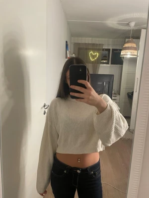 Vit croppad stickad tröja - Säljer en vit croppad stickad tröja med breda, långa ärmar och ribbad struktur. Tröjan har en avslappnad passform och är perfekt för dig som gillar en trendig och bekväm stil. Passar snyggt till både jeans och kjol. Fråga gärna om fler bilder eller mått!