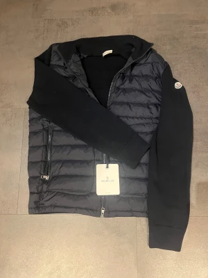 Moncler cardigan - Säljer en Moncler cardigan i färgen navyblue i nyskick i storlek xl då den är för stor för mig. Väldigt fin med scan på armen bara skriva om ni undrar eller vill ha bild på något