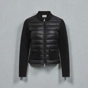 Moncler cardigan (Äkta) - Svart pufferjacka från Moncler med quiltad front och stickade ärmar. Jackan har två framfickor, ribbad krage och detaljer vid ärmslut. Dragkedja med Moncler-logga framtill. Perfekt för dig som vill ha en clean och stilren look.