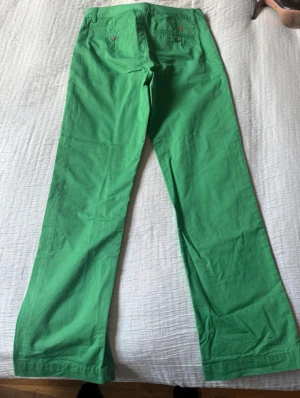 Gröna chinos från Polo Ralph Lauren - Snygga gröna chinos från Polo Ralph Lauren med klassisk orange logga broderad ovanför bakfickan. Byxorna har raka ben och knappstängning vid fickorna. Tillverkade i mjuk bomull som är skön att bära. Perfekt för dig som vill sticka ut med färg. Length is 99cm, Waist is 37cm. 100% authentic.