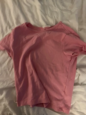 Rosa basic t-shirt i bomull - En enkel rosa t-shirt med rund hals och korta ärmar. Modellen är klassisk och passar perfekt till jeans eller shorts. Materialet är mjukt och skönt bomull som känns nice mot huden. Perfekt för dig som gillar en clean och chill stil.