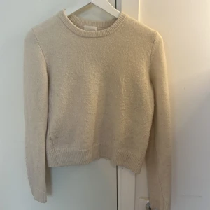 Vit stickad tröja från H&M - Mysig vit stickad tröja från H&M med rund halsringning och ribbade muddar. Tröjan är i storlek s men funkar också för xs. Köptes för cirka 200 kr. Har ett litet hål på framsidan men syns knappt