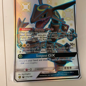 Rayquaza GX (177a/168) - Cool och glittrig Rayquaza GX Pokémonkort! Perfekt för samlare och spelare som vill boosta sitt deck med en legendarisk drake. Kortet har unika attacker och en snygg holo-effekt som gör det extra speciellt. Ett måste för alla Pokémon-fans!