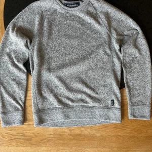 Grå sweatshirt från Abercrombie - Snygg grå sweatshirt från Abercrombie med rund hals och långärmad design. Tröjan har en melerad look och är tillverkad i mjuk bomullsmix som känns skön mot huden. Passformen är normal och den funkar perfekt till jeans eller joggers.
