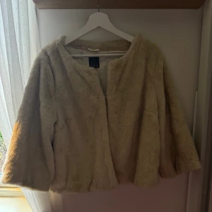 Beige pälsjacka med trekvartsärm - Säljer en fluffig beige pälsjacka med trekvartsärmar. Jackan ger en  lyxig känsla och är i fint skick. Perfekt för dig som vill sticka ut och hålla dig varm under kyliga dagar.