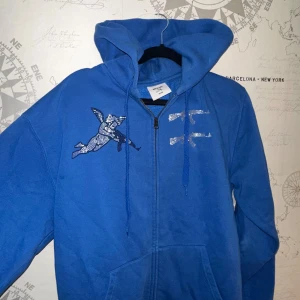 Blå hoodie från One of One med strasstenar - Blå hoodie med dragkedja från One of One. Utsmyckad med strasstenar 