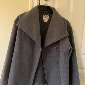 Grå kappa från Gina Tricot - Snygg grå kappa från Gina Tricot I stl 158/164 med bred krage och tre knappar framtill. Fint skick och lite använt. 100kr