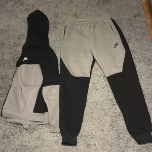 Nike tech set svart/Grå - En väldigt skön Nike Tech set i grå och svart färg. Perfekt när man känner för att ha på sig nåt som håller en varm. Materialet innuti är väldigt mjukt och nyanserna på setet är väldigt snygga. Varan är inte använd utan är i princip helt ny utan några tecken på användning. Pris kan diskuteras!