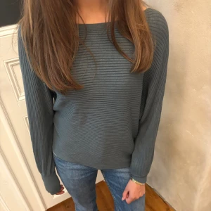 Mörkgrön ribbad tröja med långa ärmar - Säljer en mörkgrå ribbad tröja med rund hals och långa ärmar. Tröjan har en avslappnad passform och är tillverkad i ett mjukt material som känns skönt mot huden. Perfekt för dig som gillar en enkel men stilren look.