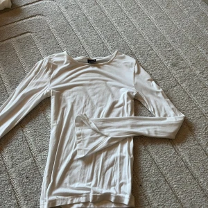 Vit långärmad topp från gina tricot - En enkel och stilren vit långärmad topp från Bik Bok. Modellen är figurnära med rund halsringning och mjukt, stretchigt material som känns skönt mot huden. Perfekt att styla med jeans eller kjol för en clean look.