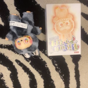 Pop Mart Bunny Secret Edition - Pop Mart Bunny Secret Edition samlarfigur med originalförpackning. Figuren är i nyskick, med färgglada ögon och mjuk pälsdräkt. Perfekt för samlare eller som dekor. Inga synliga defekter eller slitage. Boxen visar olika varianter av figuren.