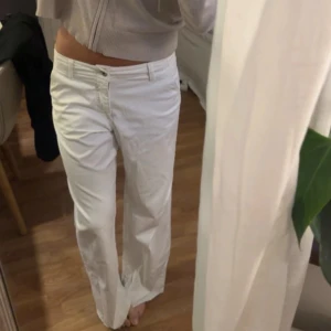 Vita wide byxor med låg midja - Säljer ett par vita byxor med låg midja och wide fit. Byxorna har klassisk femficksdesign, knapp och dragkedja framtill. Materialet är mjukt och känns som bomull, perfekt för en chill och stilren look.