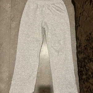 Grå mjukisbyxor med resårmidja - Ljusgrå mjukisbyxor i storlek L med resår i midjan och snörning på insidan. Byxorna har en klassisk rak passform och är tillverkade i mjukt bomullsmaterial, perfekta för chill dagar hemma eller när du vill vara extra bekväm. De har inga fel eller repor någonstans den är typ i perfekt skick