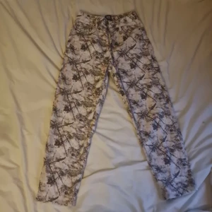 Mönstrade jeans från BDG Urban Outfitters - Säljer ett par unika jeans från BDG Urban Outfitters med grymt camouflageinspirerat mönster i beige, brunt och svart. Klassisk femficksmodell med raka ben och normal passform. Perfekta för dig som vill sticka ut med din stil.