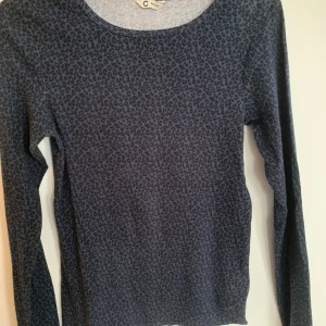 Mörkblå leopardmönstrad långärmad tröja - Snygg långärmad tröja i mörkblått med leopardmönster. Tröjan har rund halsringning och är i ett mjukt, stretchigt material som sitter skönt på kroppen. Perfekt för dig som vill ha en cool och trendig look.