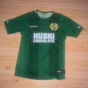 Grön Hammarby fotbollströja Craft S - Säljer en grön Hammarby fotbollströja från Craft i storlek S. Tröjan har vita detaljer vid kragen, klubbmärke på bröstet och sponsortryck 'Huski Chocolate' på framsidan. Tillverkad i lätt och ventilerande polyester, perfekt för match eller träning.
