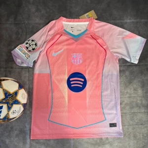 Barcelona Lamine Yamal #10 rosa matchtröja - Snygg Barcelona fotbollströja med Lamine Yamal och nummer 10 på ryggen. Tröjan är rosa med ljusa och blå detaljer, har korta ärmar och coola linjemönster. Officiella klubbmärket, Nike-logga och Spotify sponsor på bröstet. Tillverkad i lätt, ventilerande polyester.