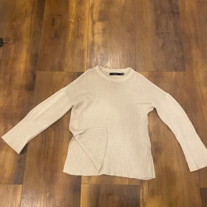 Beige stickad tröja från Vero Moda - Säljer en beige stickad tröja från Vero Moda med bred ribbad kant nertill och vid ärmslut. Tröjan har en avslappnad passform och rund halsringning. Perfekt för lager-på-lager och enkel att matcha med jeans eller kjol.