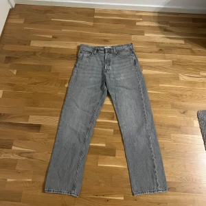 Gråa relaxed jeans från Jack & Jones - Säljer mina Jack & Jones “Relaxed Chris” jeans i grå denim. Storlek: 30/30, men de har krympt en del efter tvätt och användning – motsvarar nu ungefär en 28/29 i passform.  Jeansen har använts i nästan 2 år, och visar tydliga tecken på användning (slitage och något kortare längd), men är fortfarande helt hela och i bra vardagsskick. 