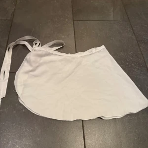 Vit omlottkjol från Wordpool - Säljer en vit omlottkjol från Wordpool i mjukt och lätt tyg. Kjolen har knytband i midjan och en flowy, kort modell. Balletkjol.