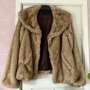 Beige pälsjacka från Vila - Säljer en fluffig och trendig beige pälsjacka från Vila. Jackan har bred krage, långa ärmar och är helfodrad med brunt tyg på insidan. Perfekt för dig som vill ha en statementjacka med lyxig känsla och snygg siluett.
