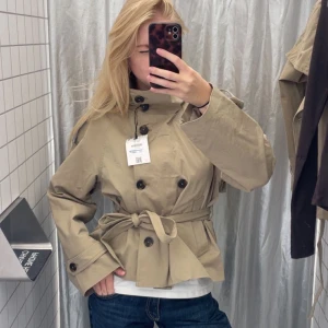 Trenchcoat Berska - Säljer en beige trenchcoat med högt krage, ”fake” dubbelknäppning och knytskärp i midjan.  Jackan är i väldigt fint skick, bilderna är mina och jag är 170 cm🫶🏼