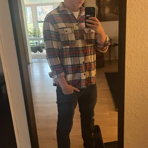 Flanell skjorta - Riktigt snygg rutig skjorta från Divided i färgerna röd, blå och vit. Skjortan har klassisk krage, knappar framtill och två bröstfickor med lock. Perfekt för en chill och avslappnad stil.